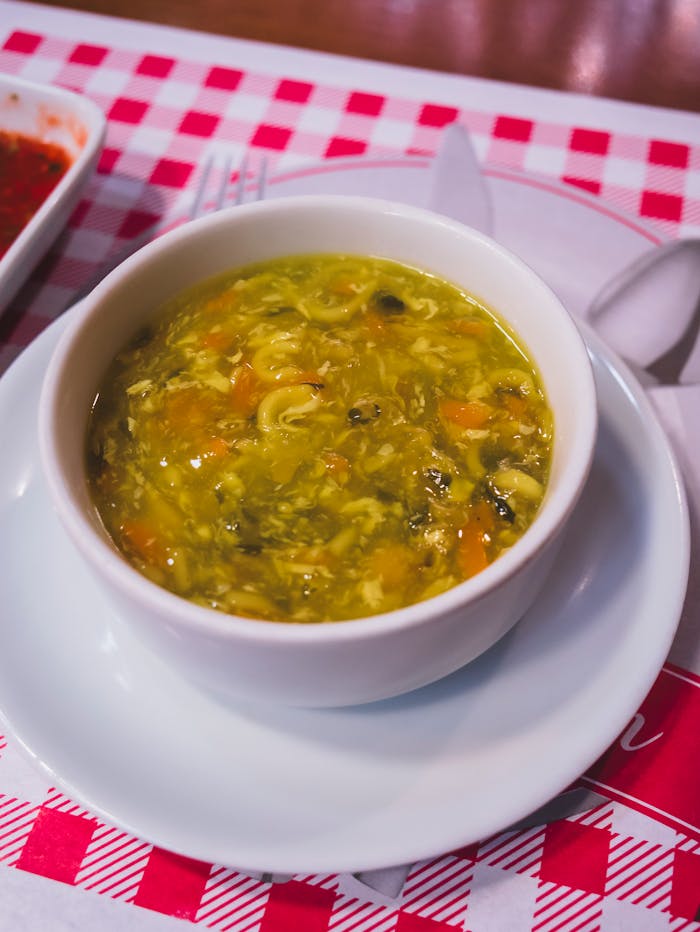 Warm and hearty homemade vegetable soup served in a white bowl on a checkered tablecloth.