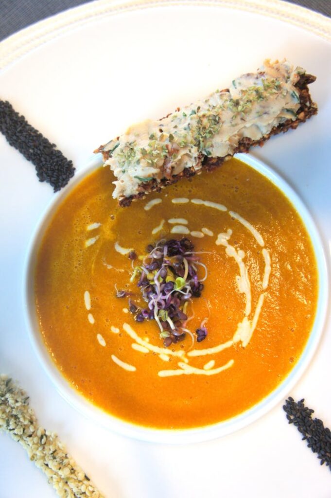 A delicious bowl of pumpkin soup garnished with herbs and cream, perfect for a cozy meal.